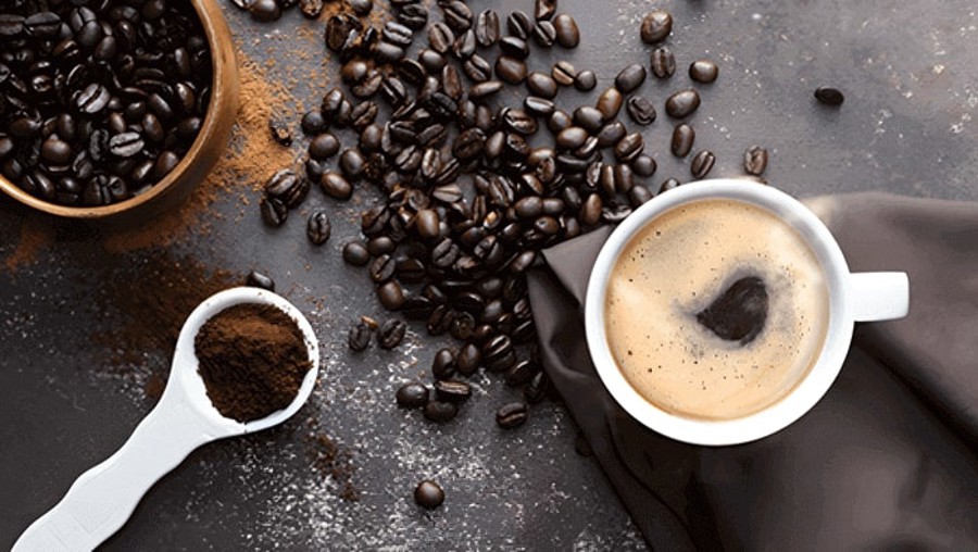 Xícara de café e grãos de café em fundo escuro. Café Caboclo com torra e moagem perfeitas.