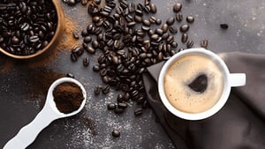 Xícara de café e grãos de café em fundo escuro