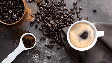 Xícara de café e grãos de café em fundo escuro