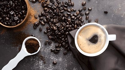 Xícara de café e grãos de café em fundo escuro